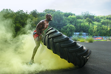 Image showing Handsome muscular man flipping big tire outdoor.