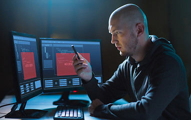 Image showing hacker with smartphone and computers in dark room