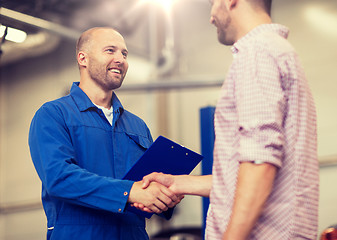 Image showing auto mechanic and man shaking hands at car shop