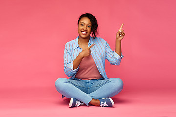 Image showing happy african american woman pointing fingers up