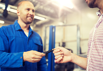 Image showing auto mechanic giving car key to man at workshop