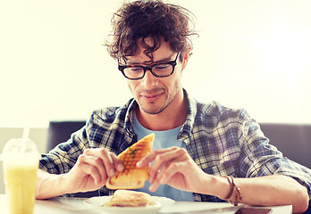 Image showing happy man eating sandwich at cafe for lunch