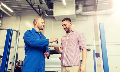 Image showing auto mechanic giving key to man at car shop