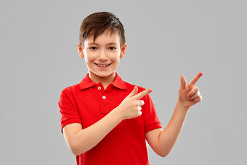 Image showing happy boy in red t-shirt pointing fingers aside