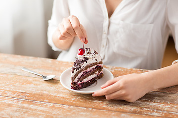 Image showing woman taking cherry from piece of chocolate cake