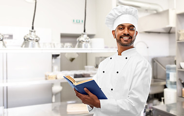 Image showing happy indian chef with cookbook at kitchen