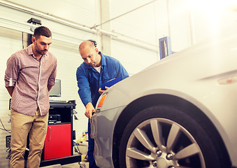 Image showing auto mechanic with clipboard and man at car shop