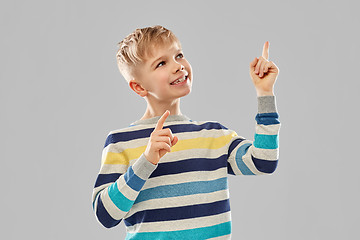 Image showing little boy in striped pullover pointing finger up