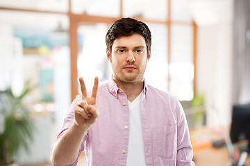 Image showing young man showing two fingers over office