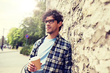 Image showing man in eyeglasses drinking coffee over street wall