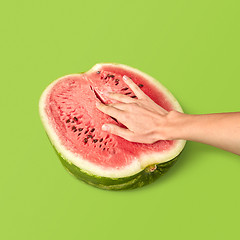 Image showing Half of ripe organic watermelon with woman\'s fingers inside.