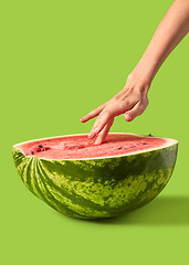 Image showing Woman\'s hand touches ripe fresh organic watermelon puree.