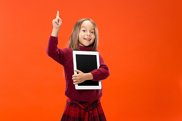 Image showing Little funny girl with tablet on studio background