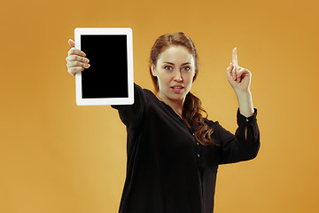 Image showing Portrait of a confident casual girl showing blank screen of laptop isolated over studio background