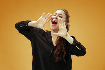 Image showing Isolated on orange young casual woman shouting at studio