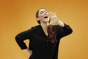 Image showing Isolated on orange young casual woman shouting at studio