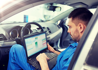 Image showing mechanic man with laptop making car diagnostic