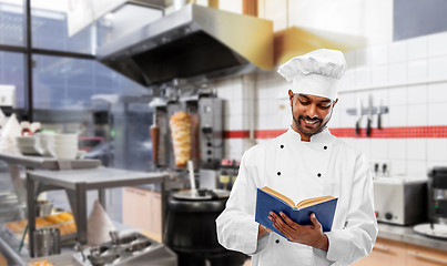 Image showing happy indian chef reading cookbook at kebab shop