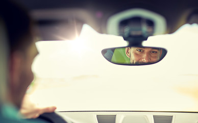 Image showing rearview mirror reflection of man driving car