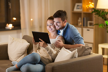 Image showing happy couple using tablet pc at home in evening