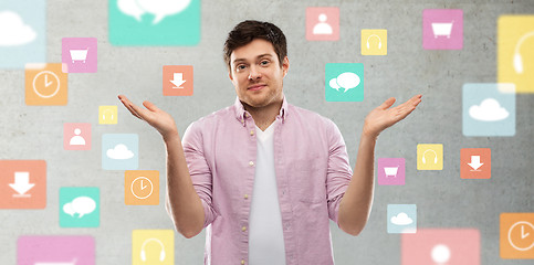 Image showing young man shrugging over app icons on grey