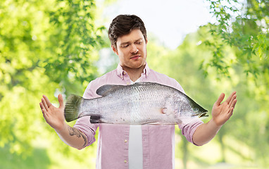 Image showing displeased young man showing size of fish