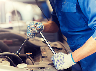 Image showing mechanic man with wrench repairing car at workshop