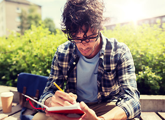 Image showing man with notebook or diary writing on city street