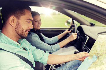 Image showing happy man and woman with road map driving in car