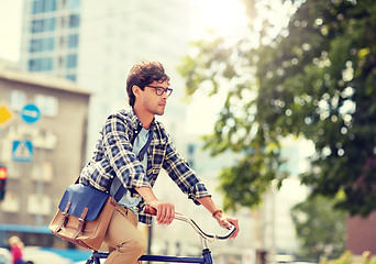 Image showing young hipster man with bag riding fixed gear bike