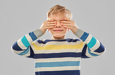 Image showing boy in striped pullover closing his eyes by hands