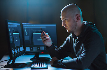 Image showing hacker with smartphone and computers in dark room