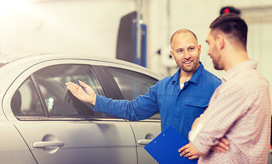 Image showing auto mechanic with clipboard and man at car shop