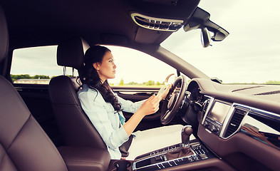 Image showing happy woman driving car with smarhphone