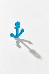 Image showing Blue emblem of anchor with long hard shadows.