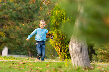 Image showing The boy happily runs through the park on the green grass