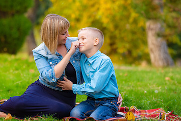 Image showing Mom tenderly took her teen\'s nose while relaxing in a clearing in a park