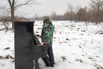 Image showing Boy playing piano outdoors