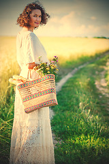 Image showing woman in white dress with basket with bread and milk walking alo