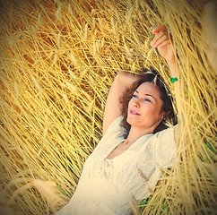 Image showing beautiful woman lies among the ears of corn in the field