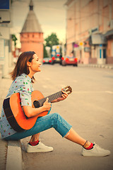 Image showing Woman in a blue shirt and jeans with a guitar in the old town