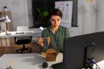 Image showing businesswoman eating and working at night office