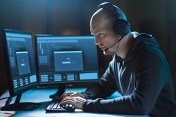 Image showing hacker with computer and headset in dark room