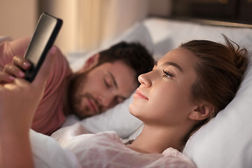 Image showing woman using smartphone while boyfriend is sleeping