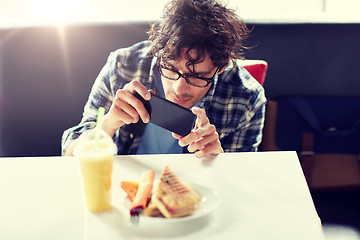 Image showing man with smartphone photographing food at cafe