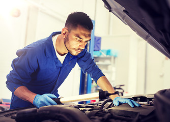 Image showing mechanic man with lamp repairing car at workshop