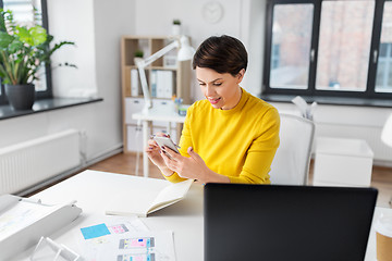 Image showing smiling ui designer using smartphone at office