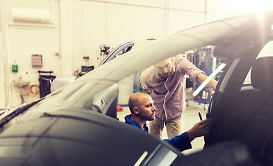 Image showing mechanic and man checking seat belt at car shop