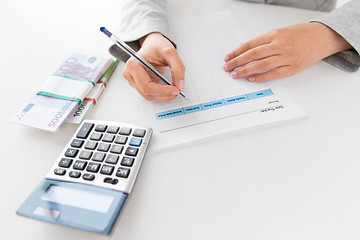 Image showing hands with tax form, calculator and money on table