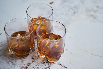 Image showing Three glasses filled with ice cubes and old aromatic whiskey
